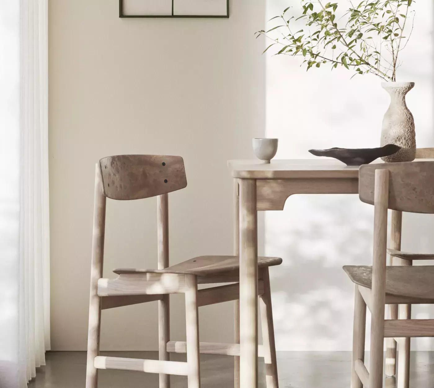 Mater black chair product next to a scenic potted plant on a white background