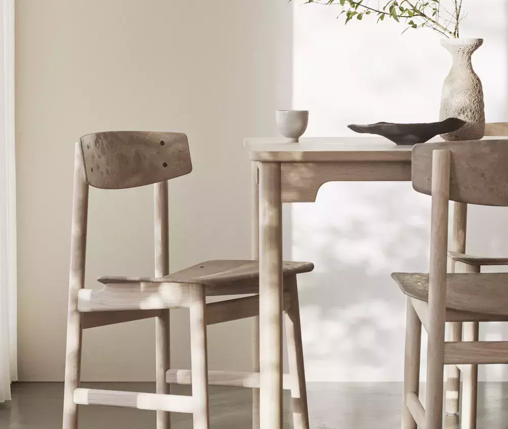 Mater black chair product next to a scenic potted plant on a white background